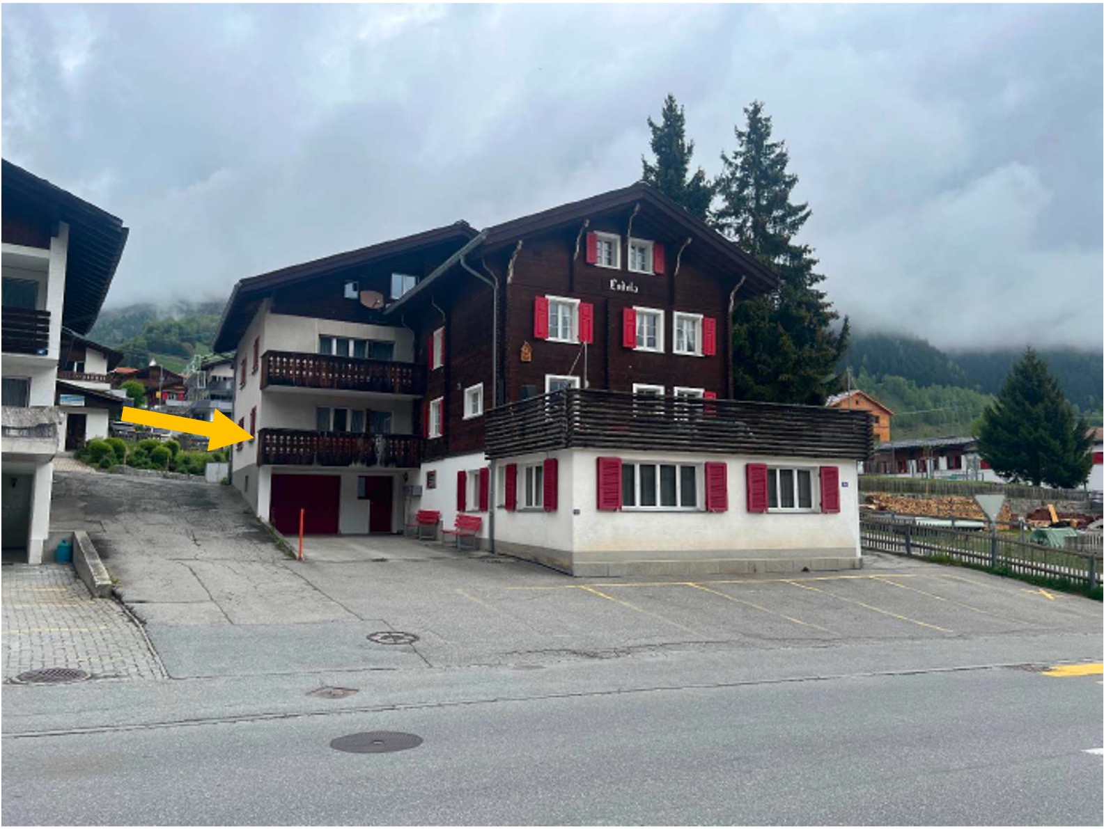 Aussenansicht des Hauses an der Via Alpsu 95 in Sedrun; ein Pfeil markiert die Wohnung